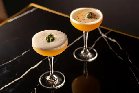 A pair of cocktails on top of a bar