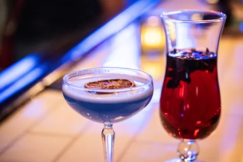 A pair of cocktails on top of a bar